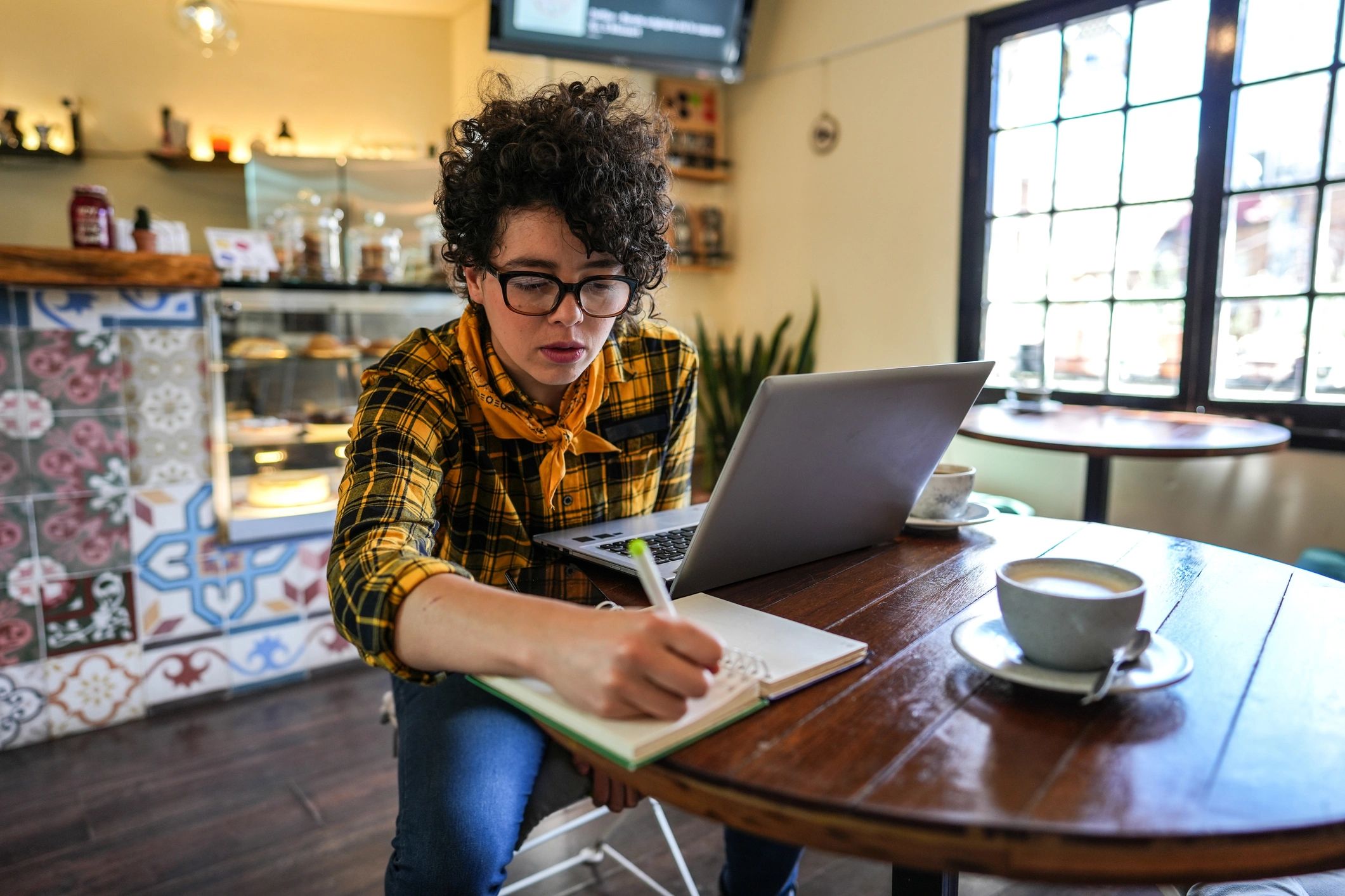 Person working thoughtfully with coffee in a cozy café
